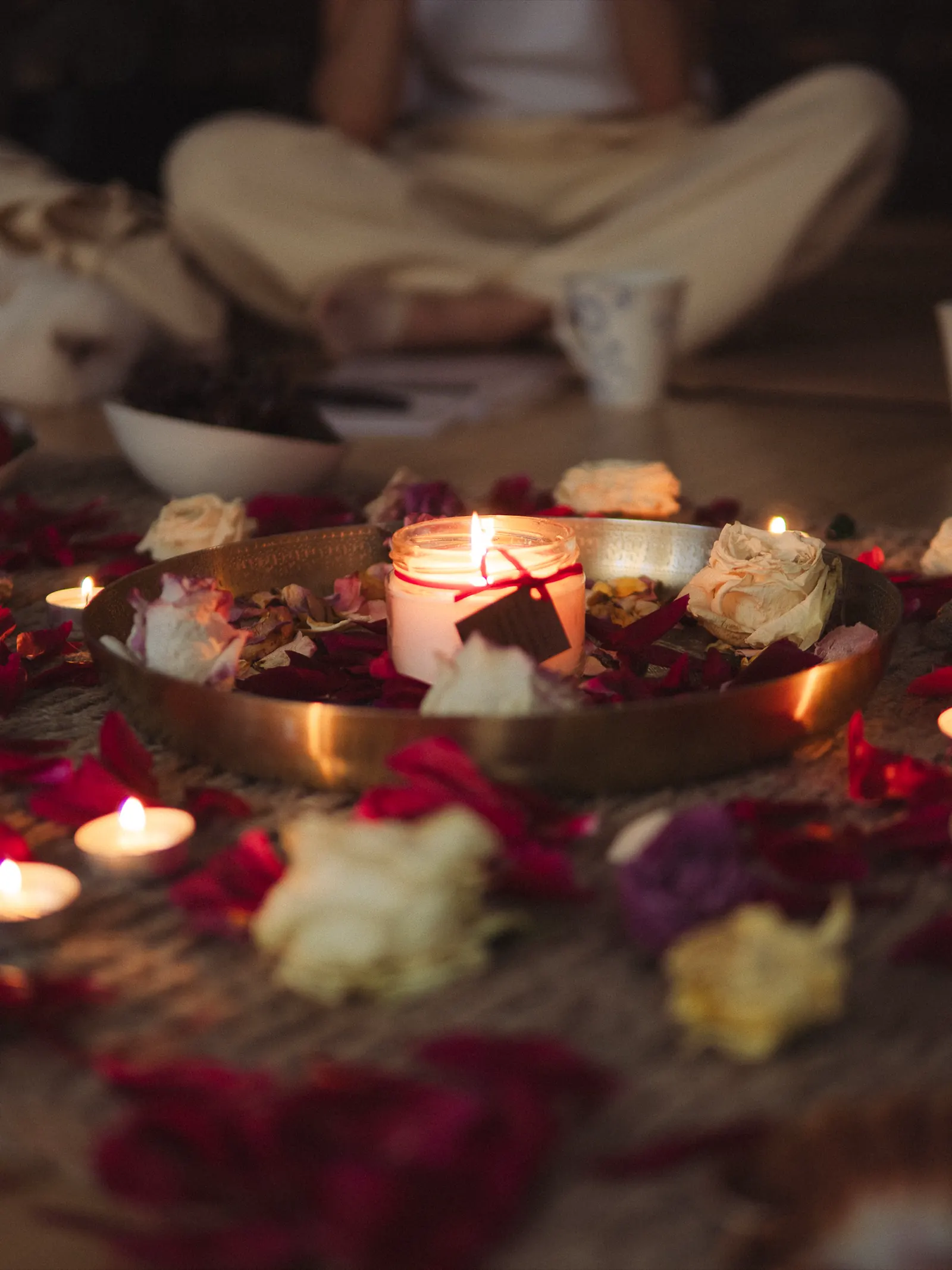 A candle altar with roses, petals, and warm ritual light.
